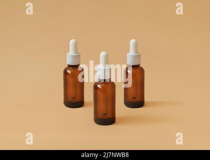 Three glass bottles with cosmetic product on beige backdrop Stock Photo