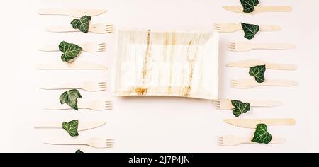 Life without Plastic.Disposable cutlery on pressed paper plate on a yellow background.Eco-friendly disposable utensils made of bamboo wood and paper Stock Photo