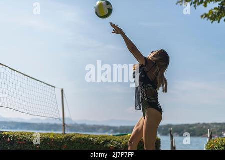 Young latin girl playing volley ball throwing the ball at a lake Stock Photo