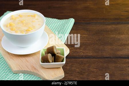 Traditional Colombian food called mazamorra,based on cooked corn dissolved in milk,accompanied with panela in pieces (sweet from sugar cane).Dark wood. Stock Photo