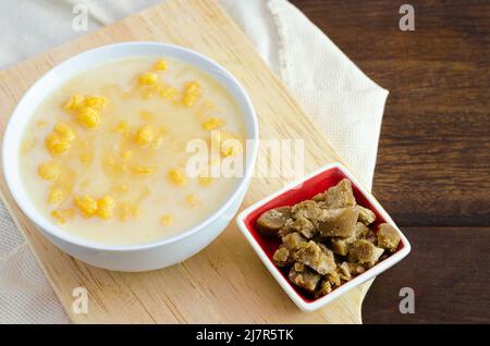 Traditional Colombian food called mazamorra,based on cooked corn dissolved in milk,accompanied with panela in pieces (sweet from sugar cane).Dark wood. Stock Photo