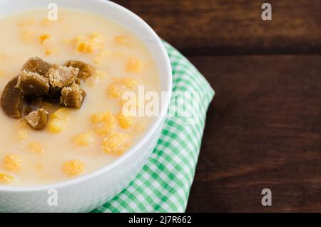 Traditional Colombian food called mazamorra,based on cooked corn dissolved in milk,accompanied with panela in pieces (sweet from sugar cane).Dark wood. Stock Photo