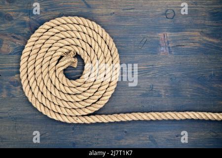 Braided natural jute rope over a rustic wood background with copy space viewed top down Stock Photo