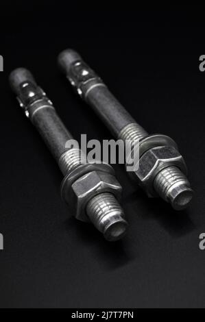 Galvanized steel metal dowel with metric bolt and nut, isolated on black background Stock Photo