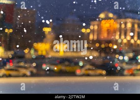blurred background with bokeh. road traffic in a big city on a winter night in heavy snow Stock Photo