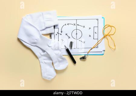 Clipboard with drawn scheme of football game, socks, marker and whistle on beige background Stock Photo