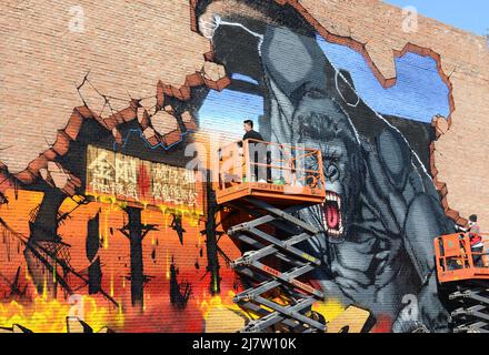 An artist painting a King Kong graffiti on on old brick factory building ( Joy Art building ) in the 798 Art Zone in Beijing, China. Stock Photo