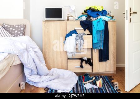 mess in a teenager's room. Clothes are strewn across the chest of drawers, floor Stock Photo