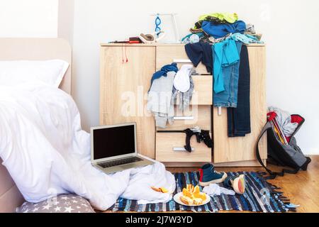 big mess in young boy's room, scattered things, unmade bed, food on floor Stock Photo