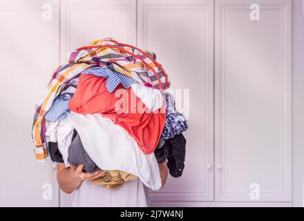 woman holds a lot of crumpled clothes in her hands, white background, copy-paste Stock Photo