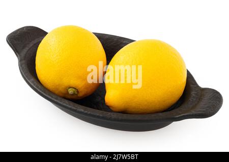 Two whole fresh lemons on black ceramic dish isolated on white. Stock Photo