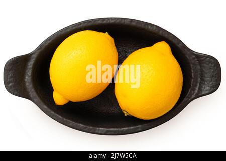 Two whole fresh lemons on black ceramic dish isolated on white. Top view. Stock Photo