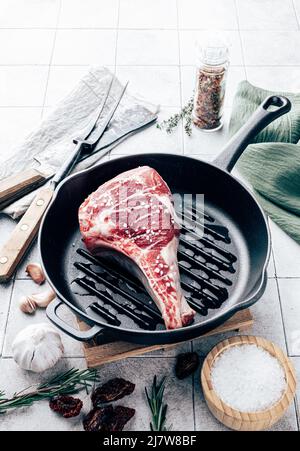 Marinated raw steak on grill pan. Tomahawk bone-steak ready to cook top view Stock Photo