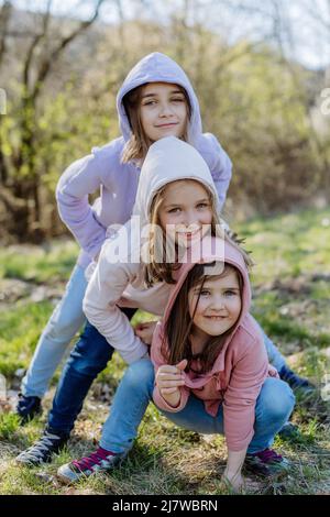 Three little sisters looking at camera in spring nature together. Stock Photo