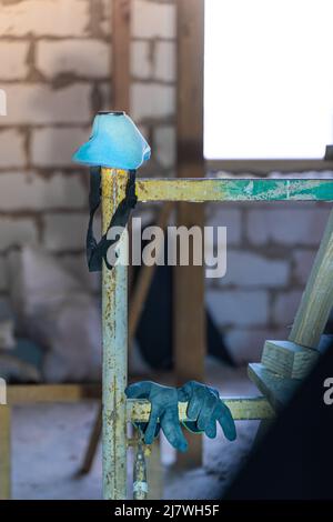 Blue respirator and rubberized black gloves hang on scaffolding, vertical photo Stock Photo