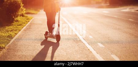 Woman riding on scooter on asphalt road in summer Stock Photo
