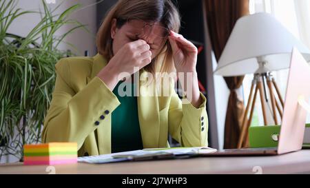 Tired business woman takes off glasses, feeling tired eyes from working at computer Stock Photo