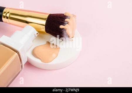 The Liquid fluid foundation glass bottle on makeup sponges and brush makeup on pink background. Stock Photo