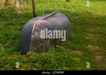 An overturned plastic boat lies on the grass Stock Photo