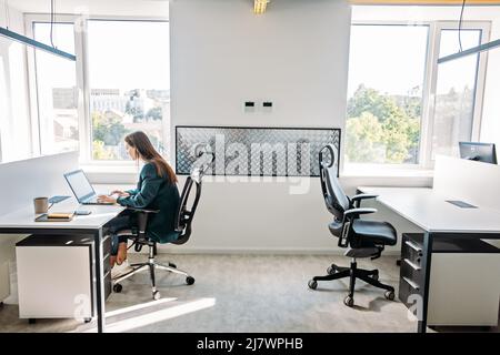 Young female programmer web developer working on computer software in modern office. Web Designer Woman working at her desk in open plan office Stock Photo