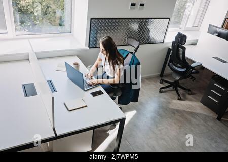 Young female programmer web developer working on computer software in modern office. Web Designer Woman working at her desk in open plan office Stock Photo