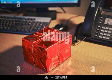 A gift box on the office desk at Christmas and New Year Eve. Surprises and gifts for the holidays Stock Photo
