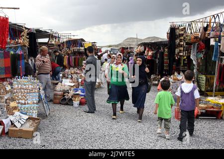 Tourists walk through a market selling souvenirs and textiles near Urgup in the Cappadocia region of Turkey. Stock Photo