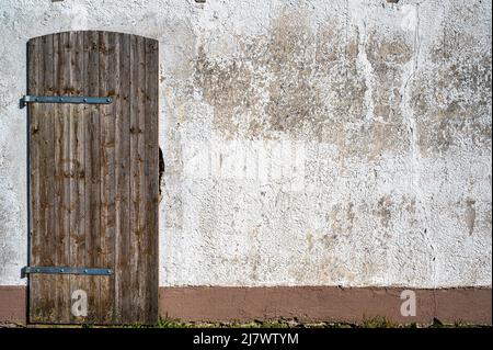Crumbling plaster and well-kept wooden door on an old shed Stock Photo
