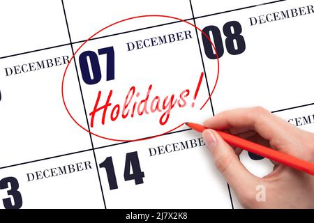 7th day of December. Hand drawing a red circle and writing the text Holidays on the calendar date 7 December. Important date. Winter month, day of the Stock Photo