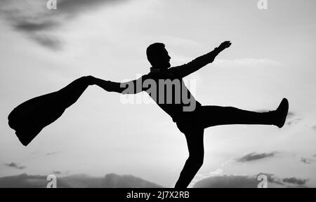 dancing man silhouette with jacket against sunset sky, freedom Stock Photo