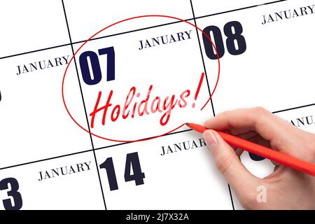 7th day of January. Hand drawing a red circle and writing the text Holidays on the calendar date 7 January. Important date. Winter month, day of the y Stock Photo