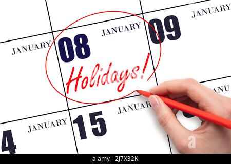 8th day of January. Hand drawing a red circle and writing the text Holidays on the calendar date 8 January. Important date. Winter month, day of the y Stock Photo