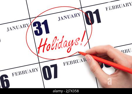 31st day of January. Hand drawing a red circle and writing the text Holidays on the calendar date 31 January. Important date. Winter month, day of the Stock Photo