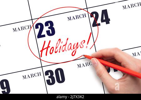 23rd day of March. Hand drawing a red circle and writing the text Holidays on the calendar date 23 March. Important date. Spring month, day of the yea Stock Photo