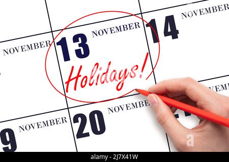 13th day of November. Hand drawing a red circle and writing the text Holidays on the calendar date 13 November. Important date. Autumn month, day of t Stock Photo
