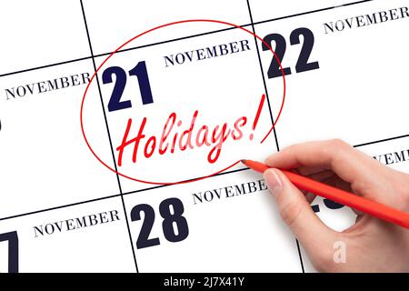 21st day of November. Hand drawing a red circle and writing the text Holidays on the calendar date 21 November. Important date. Autumn month, day of t Stock Photo