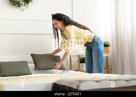 Portrait of cheerful young woman making bed after wake up Stock Photo