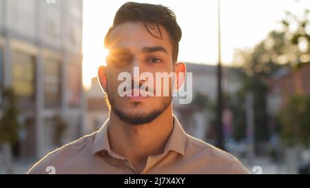 Portrait male calm serious face outdoors on street in city sunlight background. Hispanic arabic bearded guy business man successful entrepreneur Stock Photo
