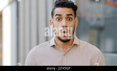 Portrait of hispanic arabian shocked bearded business man entrepreneur looking at camera opens mouth wide in surprise of unexpected news shouts. Close Stock Photo