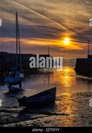The sun sets between the harbour walls at Aberaeron, Cardigan Bay, Wales. Stock Photo