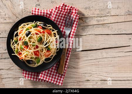 Spaghetti with vegetables(broccoli,tomatoes,peppers) on wooden table Stock Photo