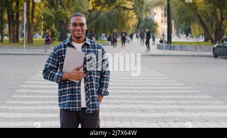 Successful young afro american business man guy african student in sunglasses stands in city street walking crosswalk road traffic car pedestrian Stock Photo