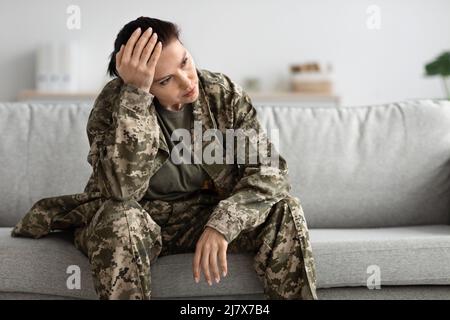 Impact Of Military Service. Depressed Pensive Female Soldier Sitting On Couch Stock Photo