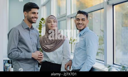 Smiling millennial multiracial employees talking gossips during break in office, young diverse multiethnic professional colleagues speak laughing Stock Photo