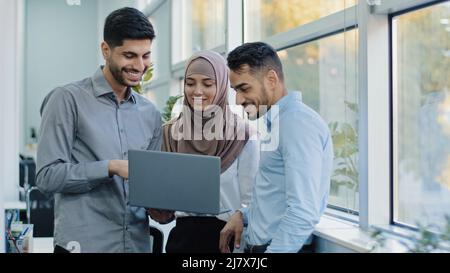 Multiethnic colleagues listens Arabic team leader explain corporate task application to diverse workers indian businesspeople looking on laptop screen Stock Photo