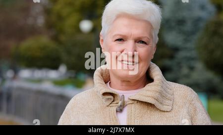 Close up portrait happy attractive benevolent woman of retirement age. Calm smiling mature lady in casual clothes with gray short hair stylish Stock Photo