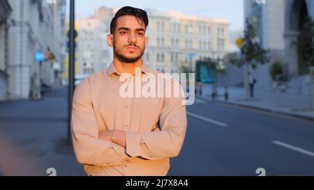 Pensive deep in thoughts thinking planning future dreaming dreamy guy business man bearded formal boss standing in city with crossed arms posing Stock Photo