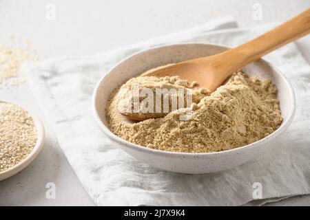 Sesame flour in white bowl for cooking gluten-free dessert. Good source of protein, minerals, natural antioxidants and vitamins. Stock Photo