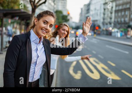Young smiling business woman catching taxi at city street. Woman looking for a taxi Stock Photo