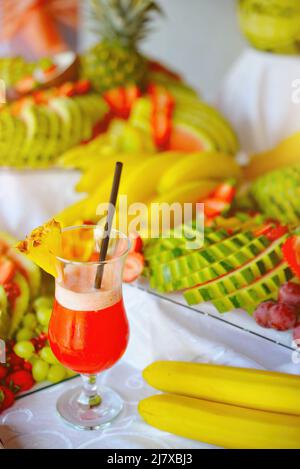 Fruit cocktail juice in glass with many tropical fruits in background Stock Photo